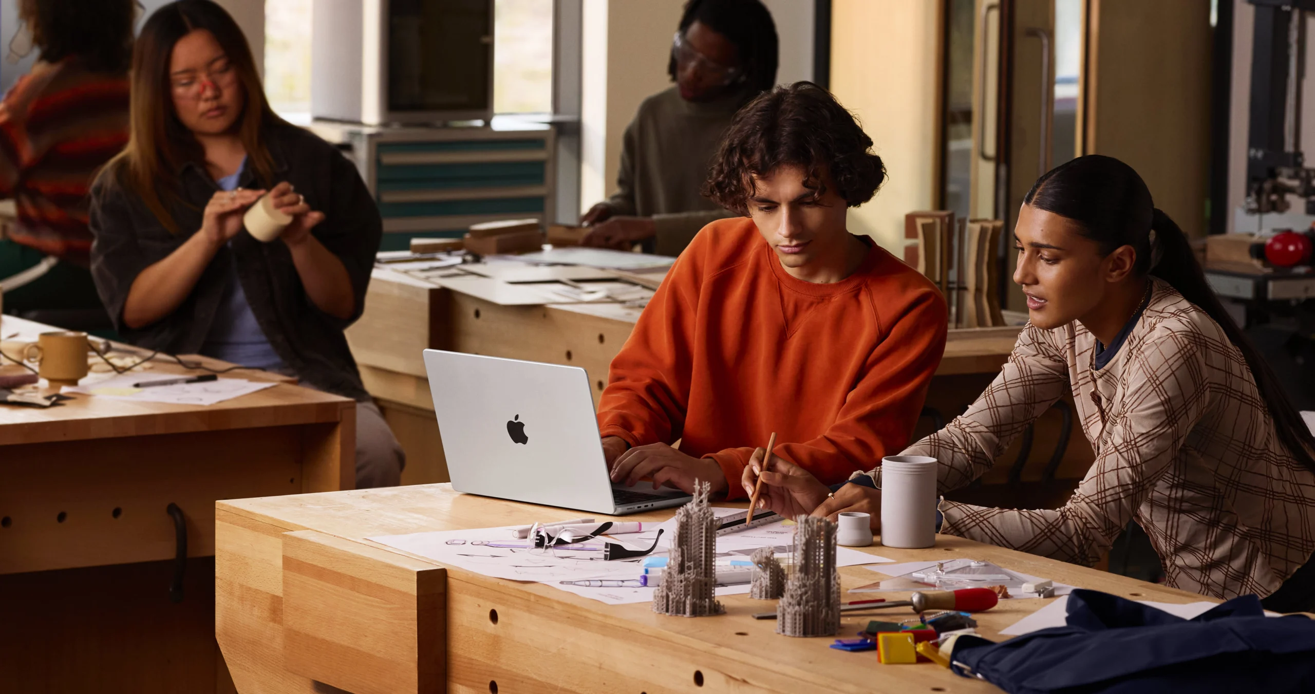 A person using his MacBook Pro with a colleague